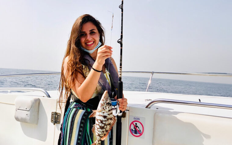 Guest holding a fish caught while casting off the stern of the boat