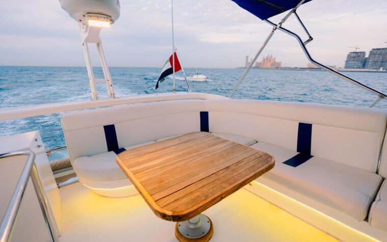 Teak dining table on the shaded aft deck, lit for an evening cruise