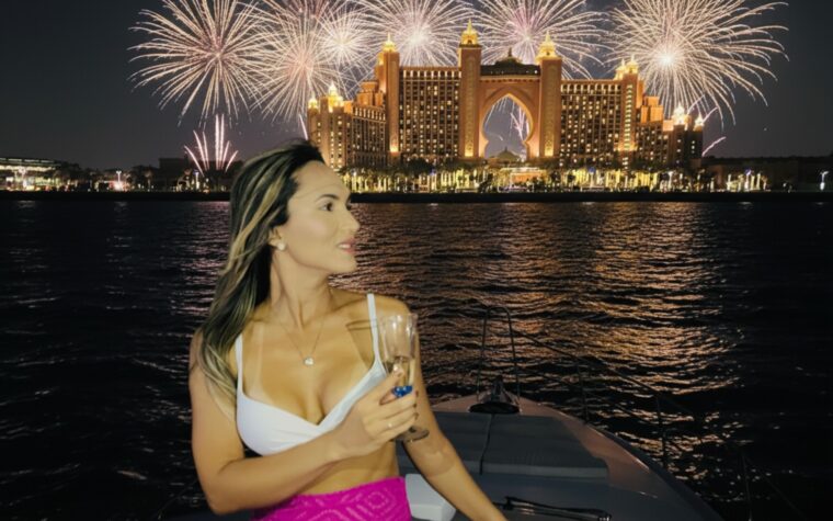 Guest with a glass of champagne as fireworks burst over Atlantis, The Palm