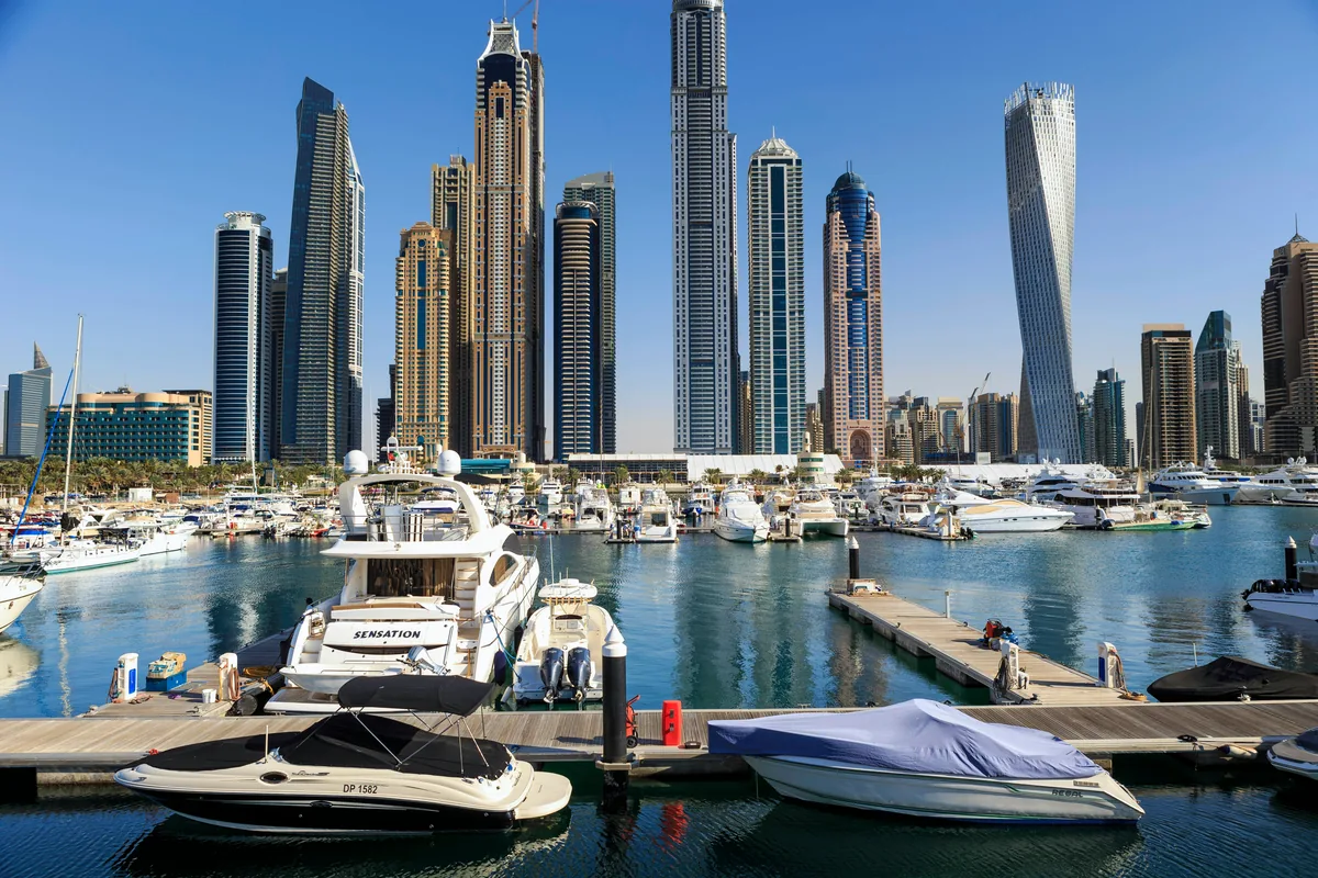 Yachts docked in a Dubai marina with a modern skyscraper skyline
