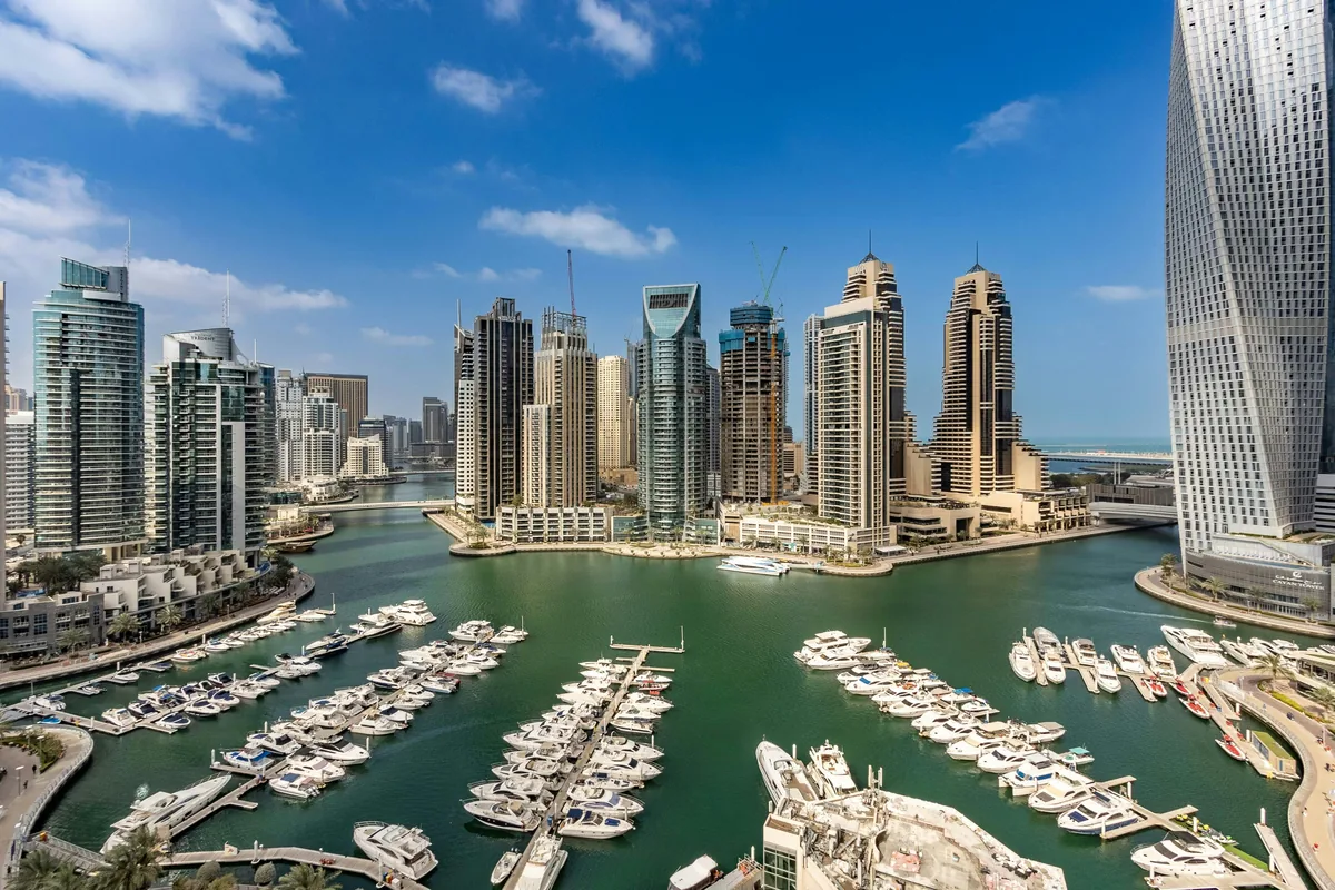 Luxury yachts docked in Dubai Marina with the Cayan Tower and modern skyscraper skyline