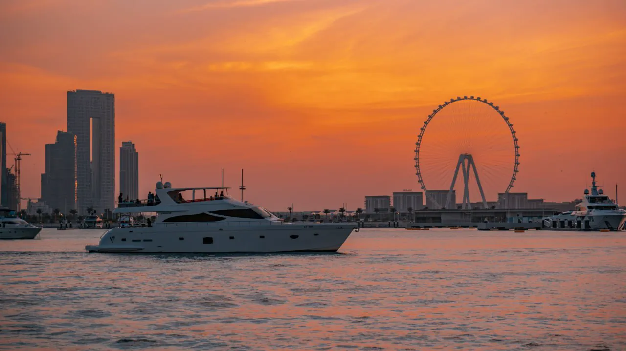 Luxury yacht at sunset in Dubai Marina with Ain Dubai Ferris wheel and skyline